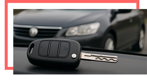 close-up transponder car key with blurred sedan in background